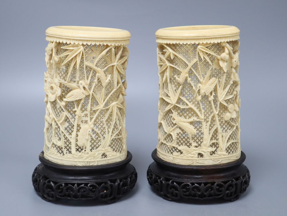 A pair of Japanese carved and pierced ivory brush pots, on hardwood stands, height 20cm